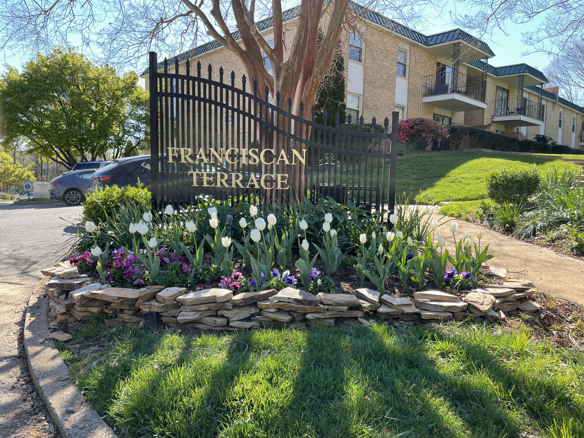 Franciscan Terrace entrance with spring tulips and iron signage